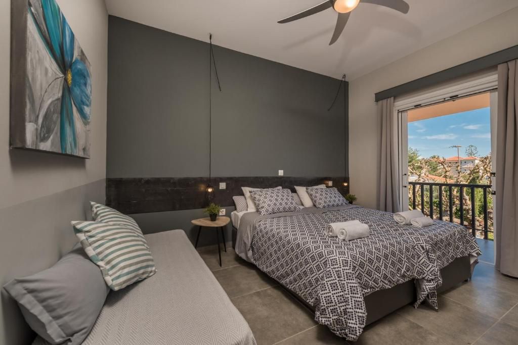 Un dormitorio moderno con una cama grande, un sofá más pequeño, un ventilador de techo y un balcón con vistas.
