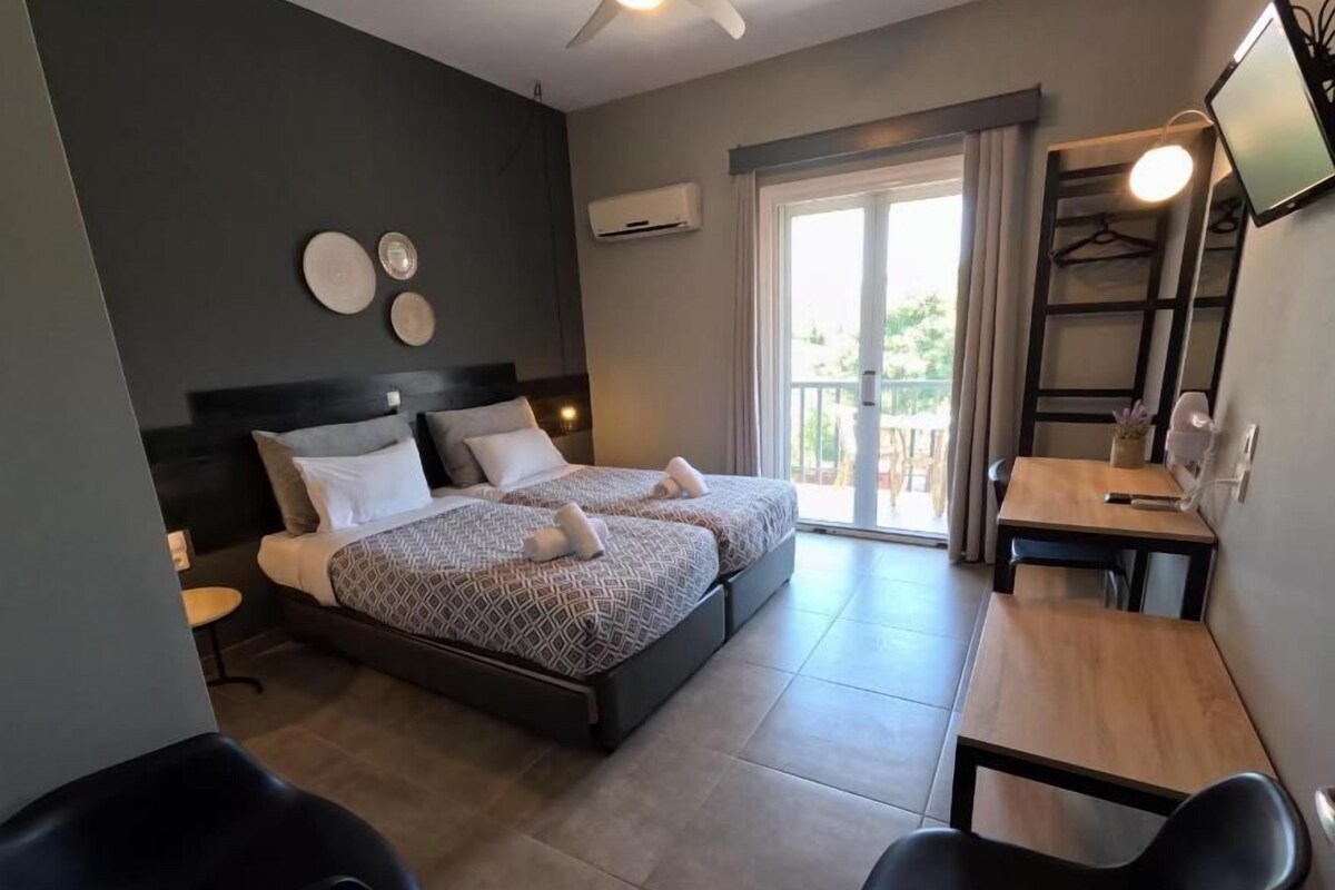 A bedroom with two beds, a desk, a chair, and a ceiling fan.