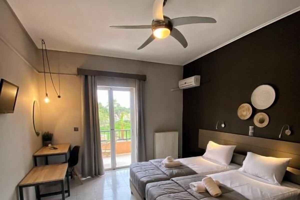 A hotel room with a bed, a desk, and a ceiling fan.