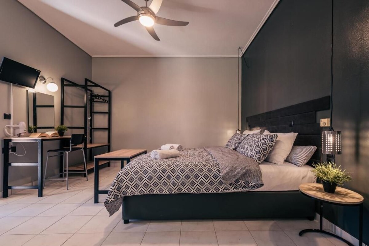 A modern bedroom with a bed, bedside table, lamp, and a desk with a chair.