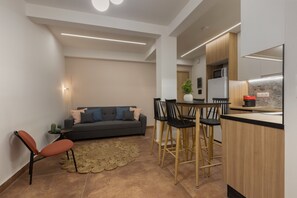 A modern kitchen with a dining area, a sofa, and a coffee table. - Minimal City View Apartment (Kallithea)