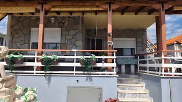 Un bâtiment doté d’une façade en pierre, d’un balcon en bois et d’un escalier menant à l’entrée.