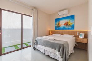 A hotel room with a bed, a painting, a nightstand, a bedside table, and a view through a sliding door. - Casa Guerreiro - Elegance in Cumbuco by Carpediem (Caucaia)