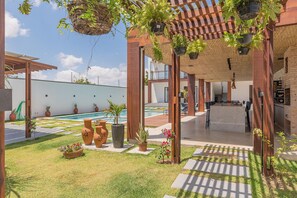 A covered outdoor area with a pool, potted plants, and a seating area. - Casa Guerreiro - Elegance in Cumbuco by Carpediem (Caucaia)