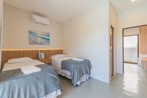 Habitación de hotel con dos camas, un cuadro en la pared y una puerta que da a otra habitación.
