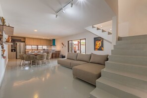 Un interior moderno con una escalera, una zona de comedor y una sala de estar.