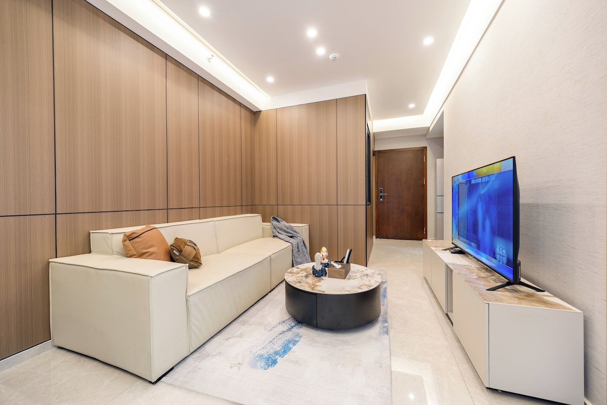 A modern living room with a sofa, a coffee table, and a television.