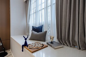 A room with a window, a cushion, a decorative item, and a book on a table.