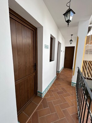 A corridor with a wooden door, tiled flooring, and a metal railing. - Country House 'Casa Aires Del Rocío' (El Rocío)