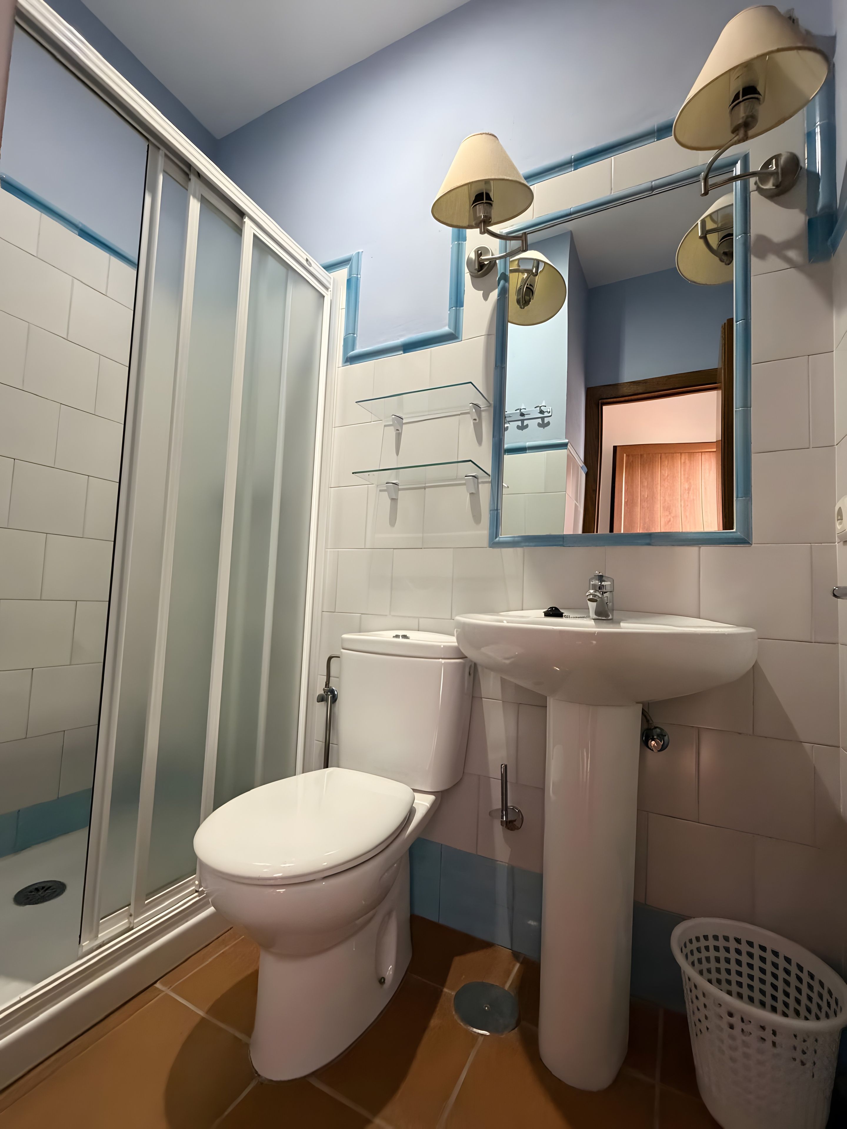 Un baño con inodoro, lavabo y zona de ducha.