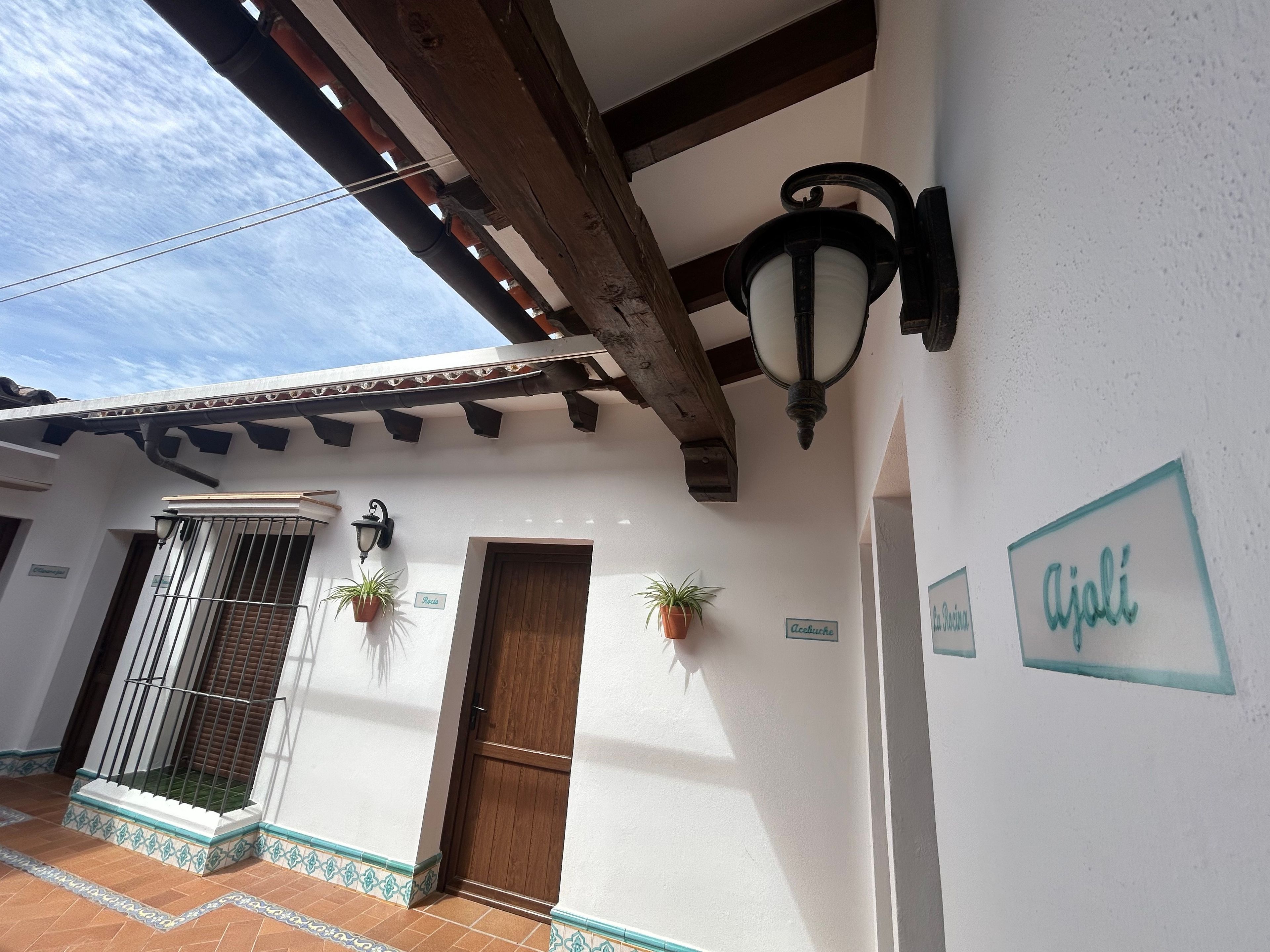 A building exterior with a wooden ceiling, a metal gate, a potted plant, and a door.