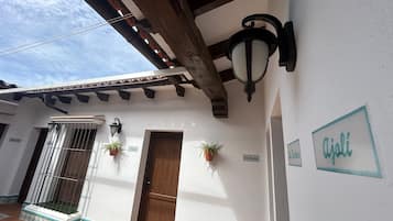 A building exterior with a wooden ceiling, a metal gate, a potted plant, and a door.