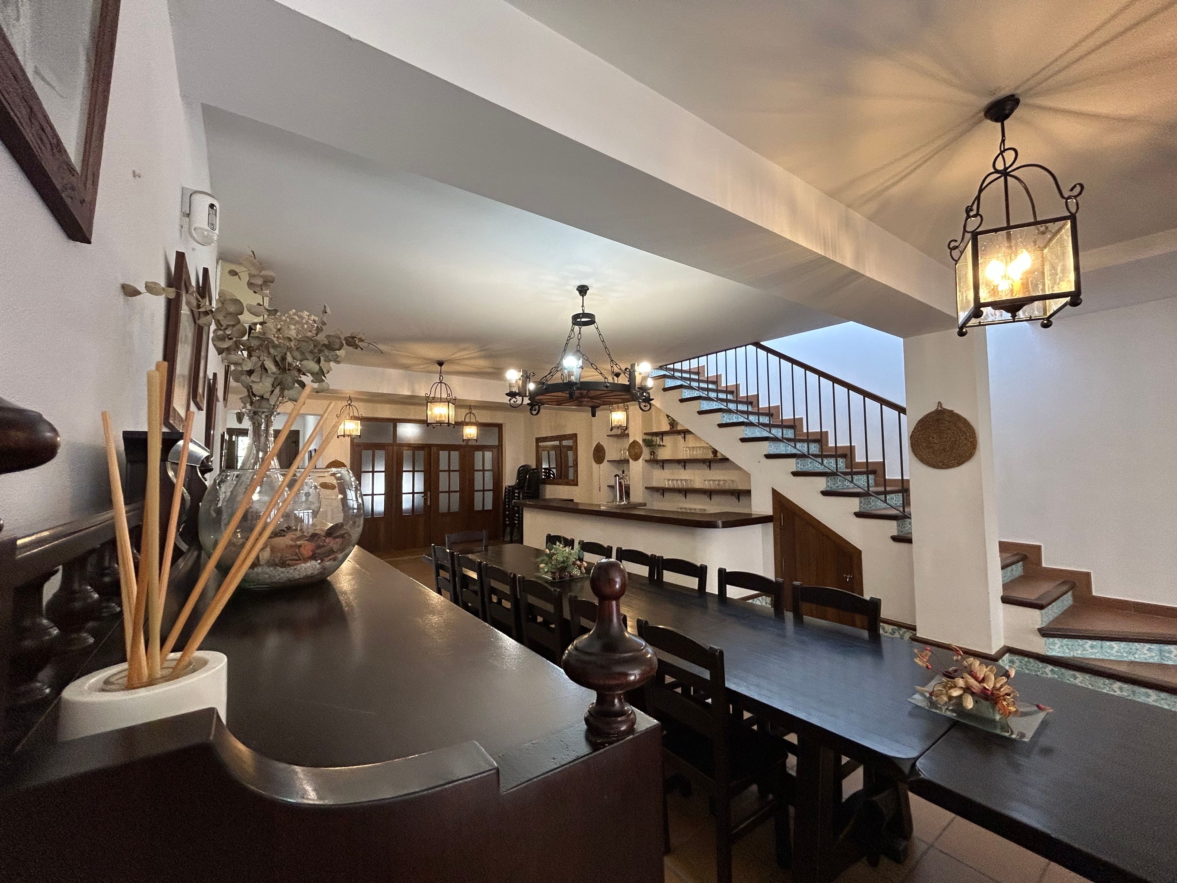 A spacious kitchen with a dining area, a staircase, and a hanging light fixture.