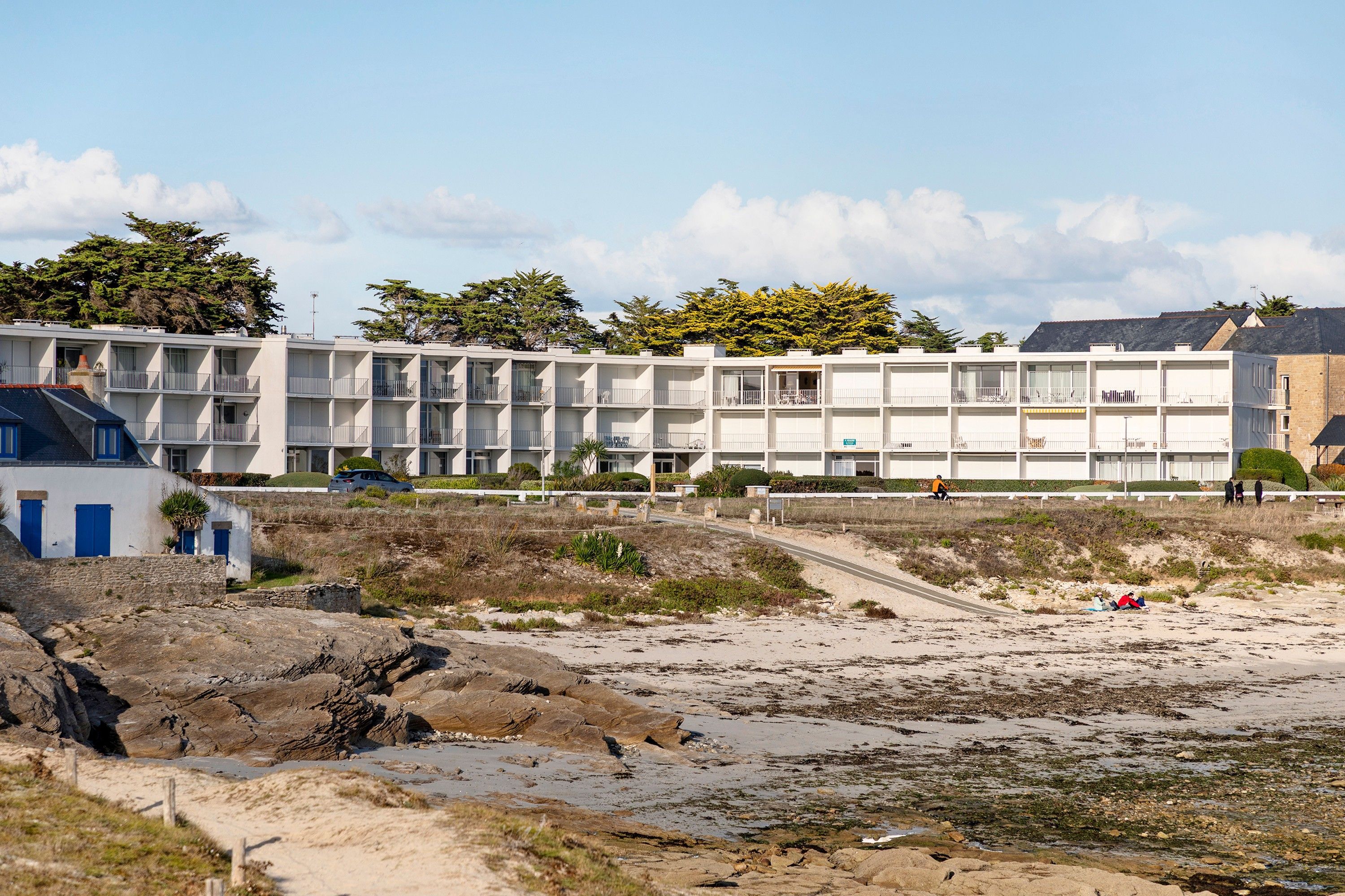 Un hôtel situé sur la côte, avec plusieurs étages, des balcons et une vue sur la plage.