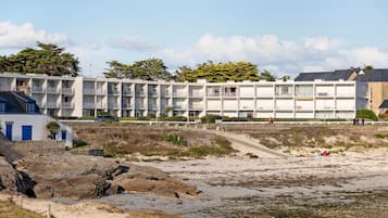 Un hôtel situé sur la côte, avec plusieurs étages, des balcons et une vue sur la plage.