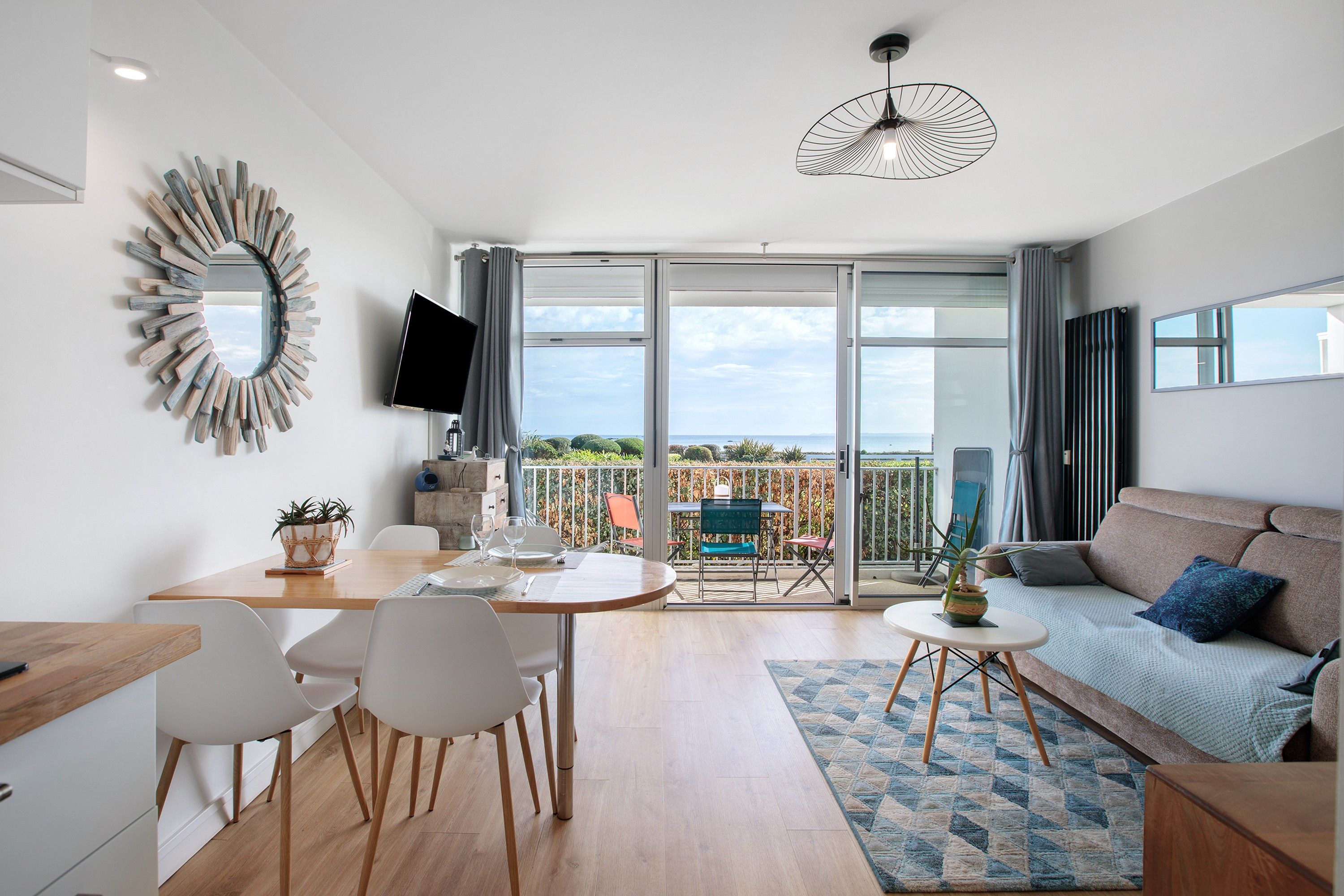 Un salon moderne comprenant un canapé, une table à manger, des chaises et un téléviseur.