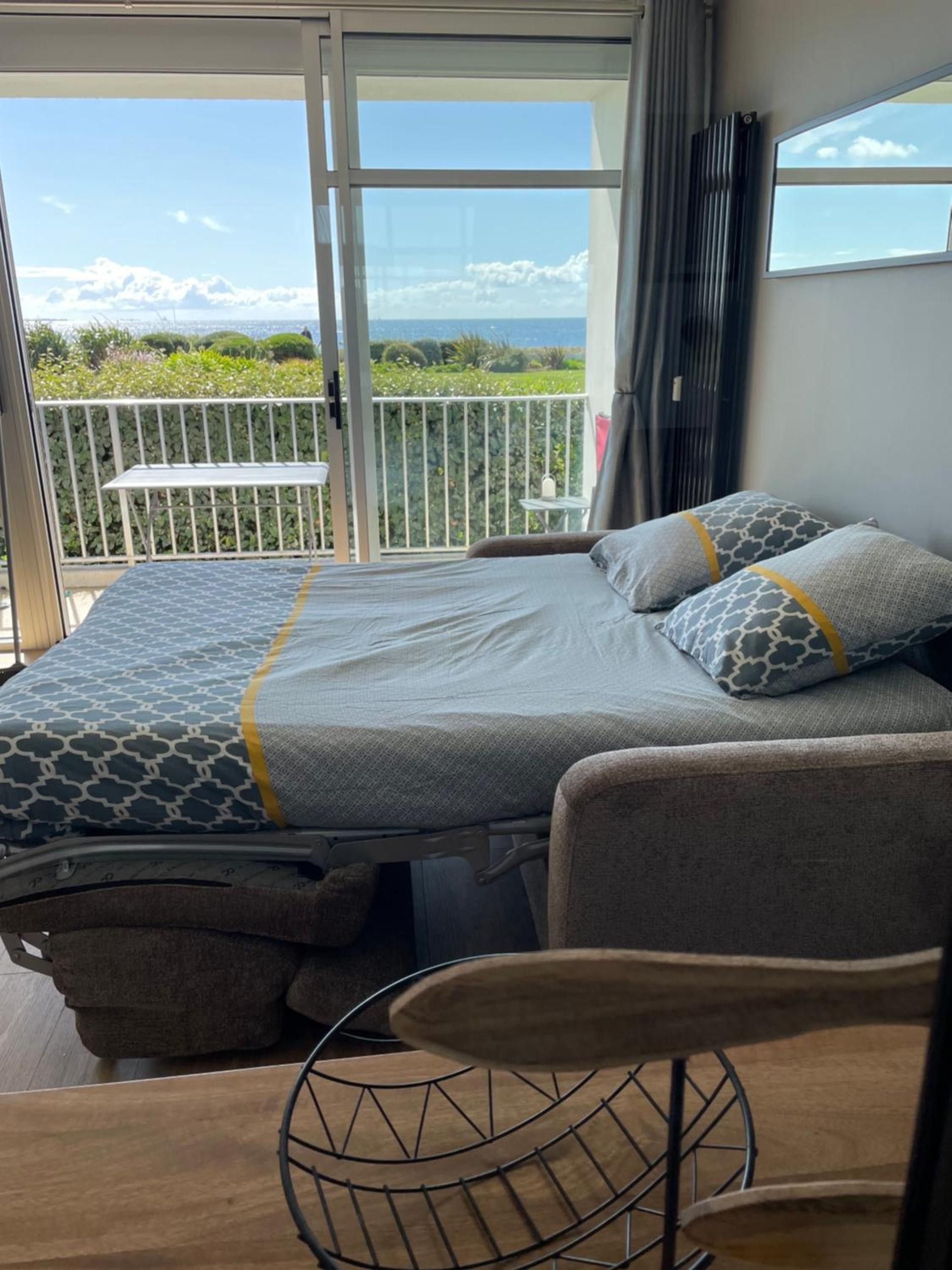 Une chambre à coucher avec un lit, une table de chevet, une chaise et une vue sur l’extérieur.