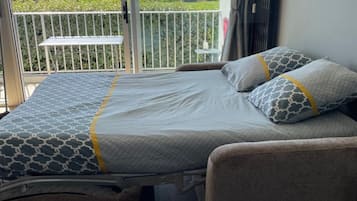 Une chambre à coucher avec un lit, une table de chevet, une chaise et une vue sur l’extérieur.