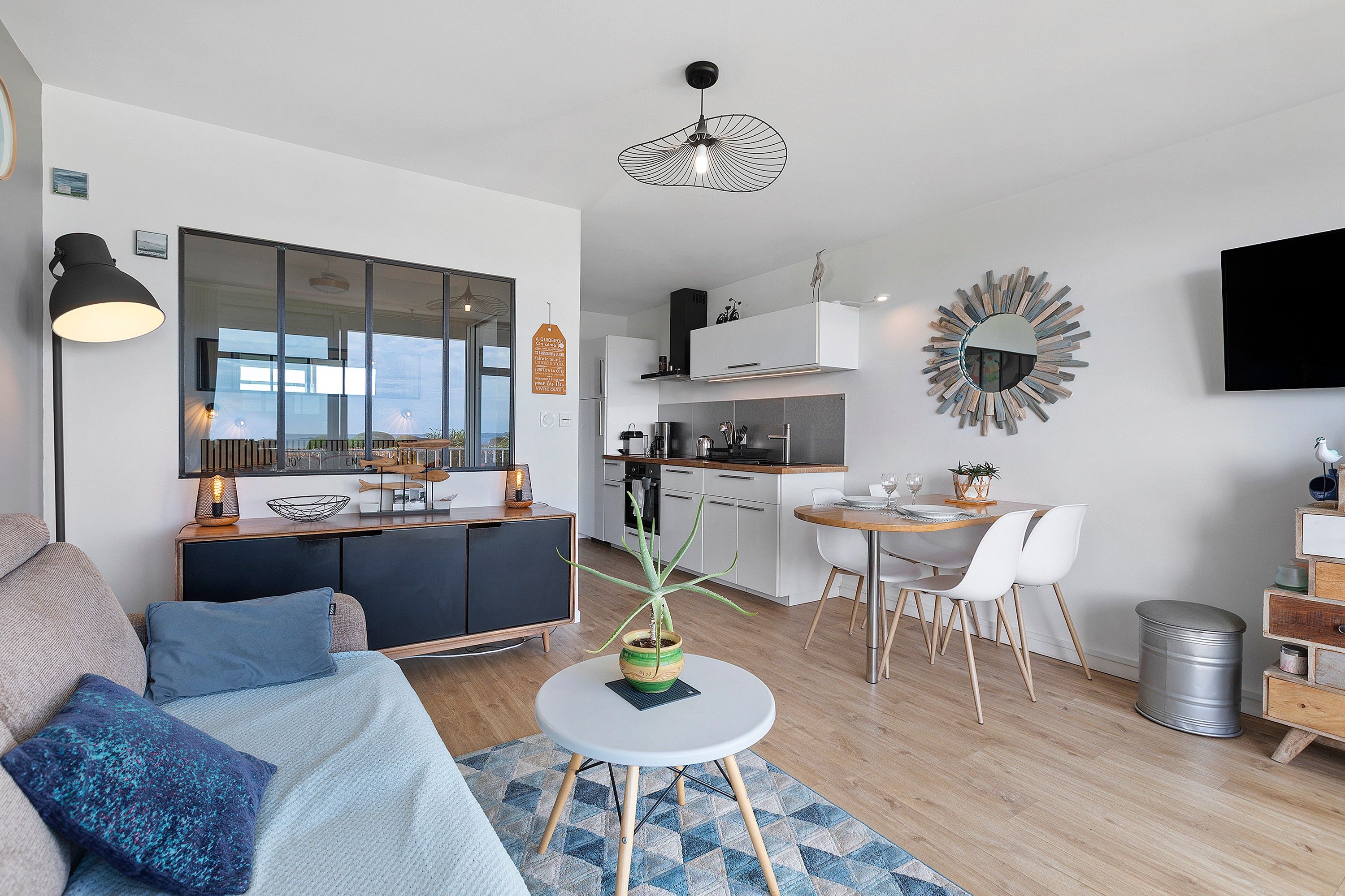 Um apartamento moderno com sala de estar, espaço para refeições, cozinha compacta e um espelho grande.