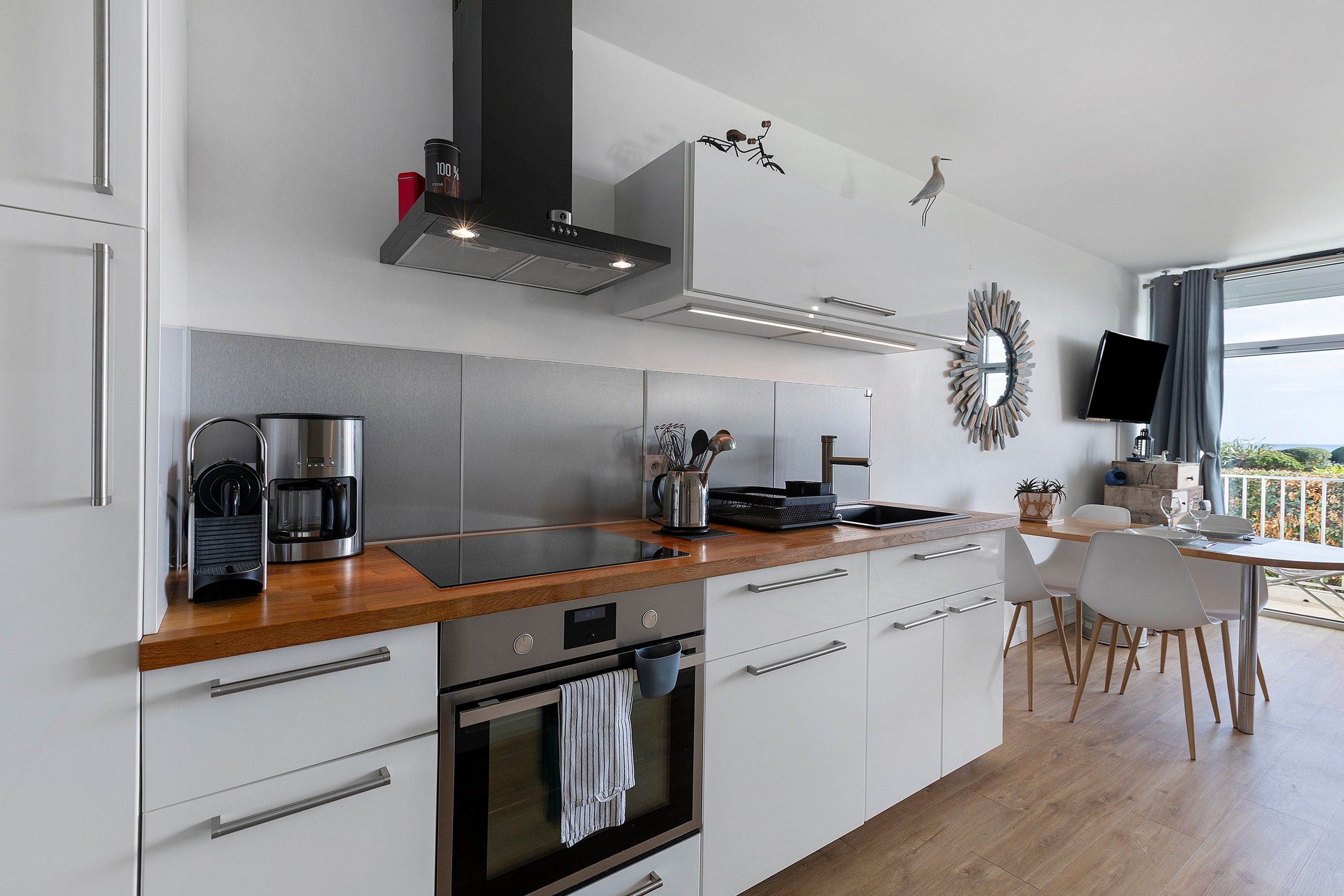 Une cuisine moderne dotée d’appareils électroménagers en acier inoxydable, d’un plan de travail en bois et d’un coin repas offrant une vue agréable.