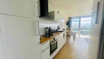 Een moderne keuken met witte kastjes, een houten aanrecht en uitzicht op het balkon.