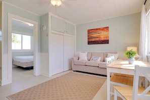 Een kamer met een bed, een slaapbank, een eettafel en een schilderij aan de muur.