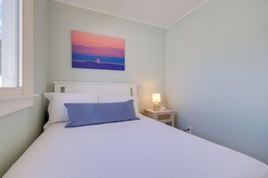 Un dormitorio con una cama, una mesita de noche con lámpara y un cuadro en la pared.