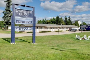 Señal de Sunrise Side Resort, con un edificio al fondo que indica 'Suites Cabinas'.