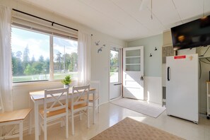 A room with a dining table and chairs, a refrigerator, a door with a window, and a view of trees outside. - Beach Access! Sunrise Side Resort Retreat (Greenbush)