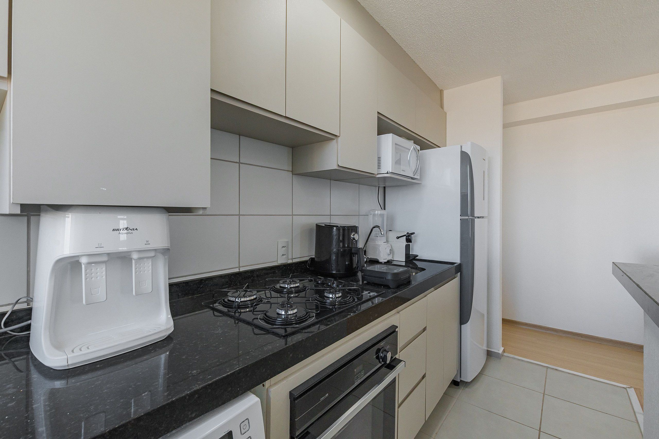A kitchen with a gas stove, a coffee maker, a microwave, and a refrigerator.