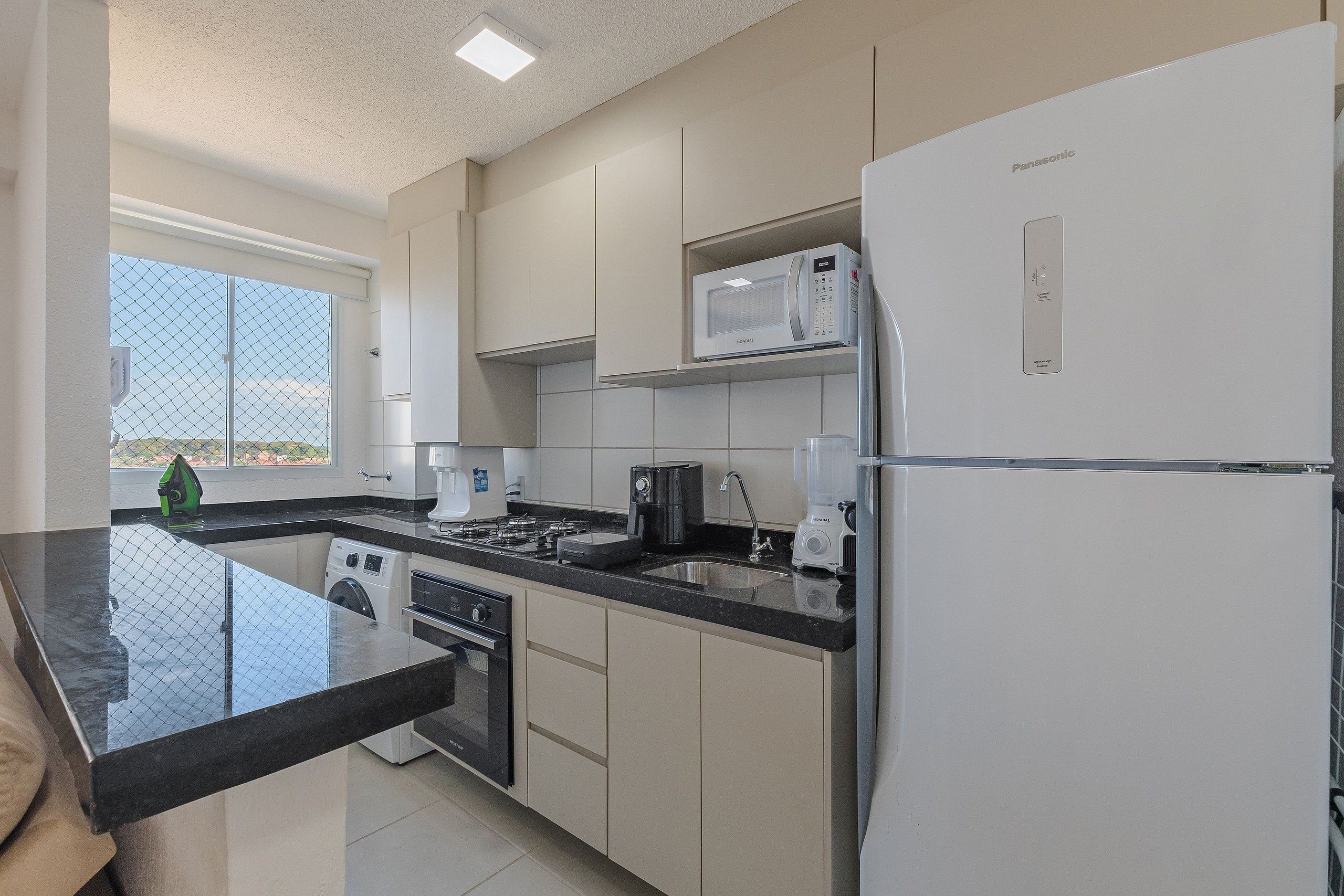 A modern kitchen with a built-in washer, a microwave, and a refrigerator.