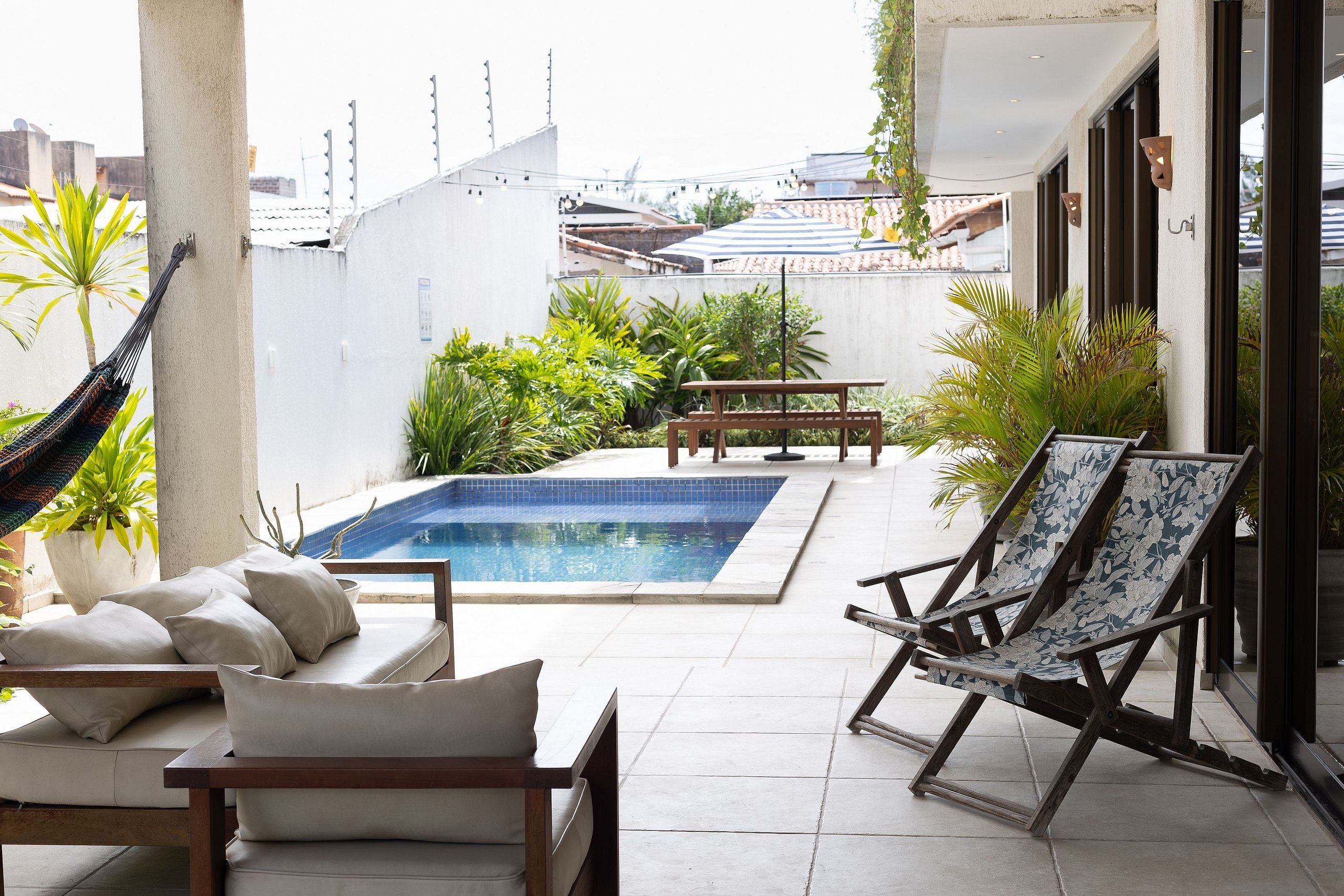 A pool area with a hammock, lounge chairs, and a table.