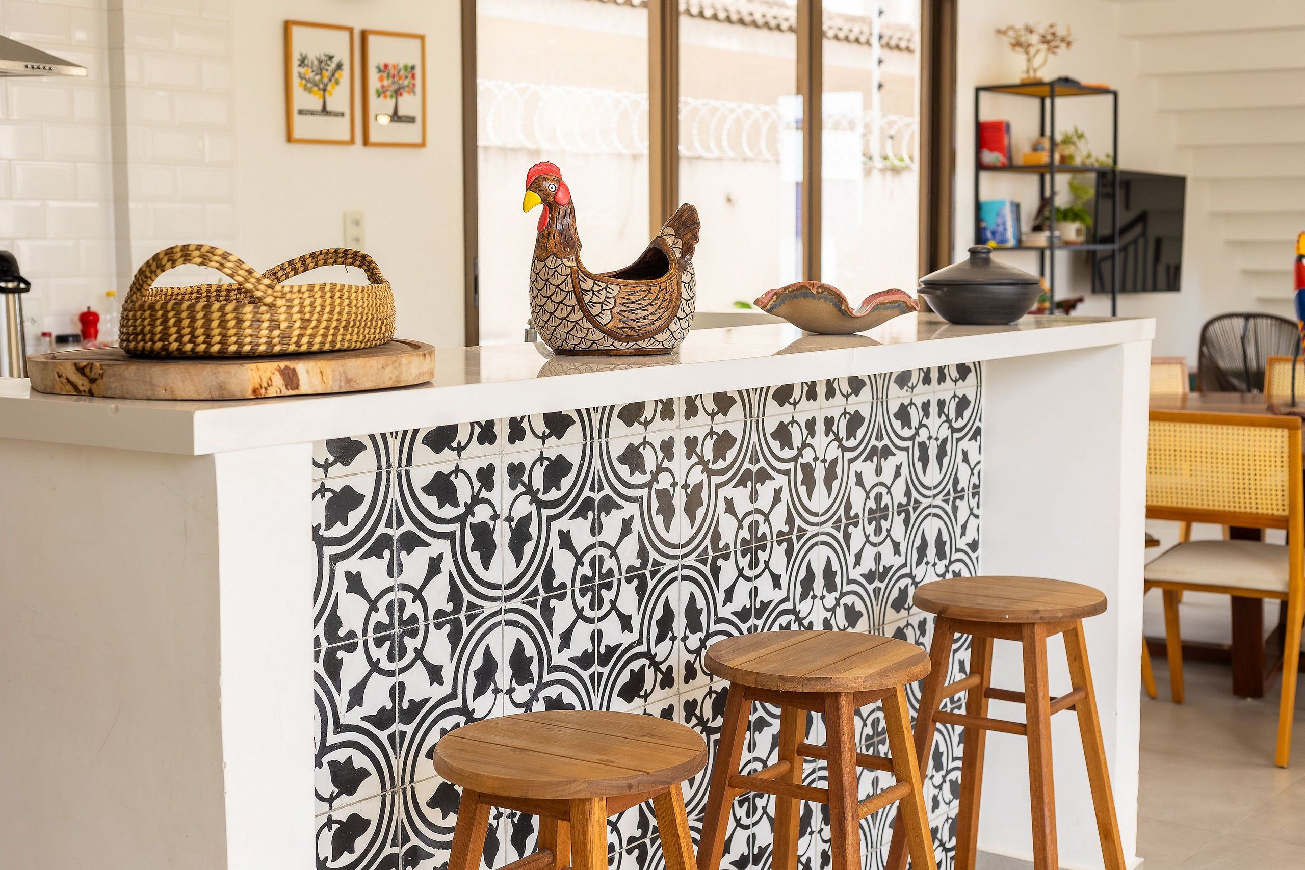 A kitchen with a white countertop, two wooden stools, and a decorative rooster.