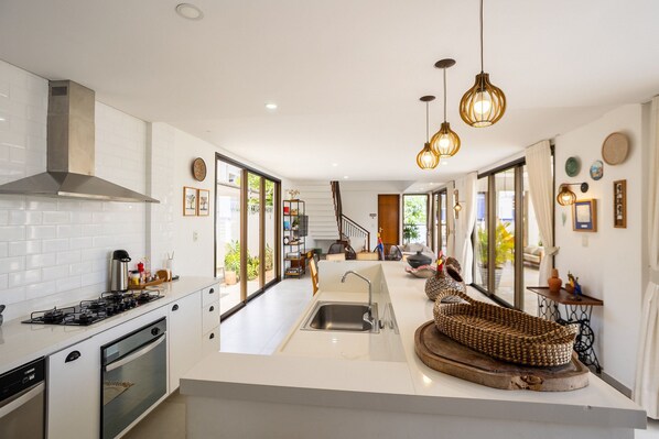 A modern kitchen with a central island, a built-in stove, and a large window providing natural light.