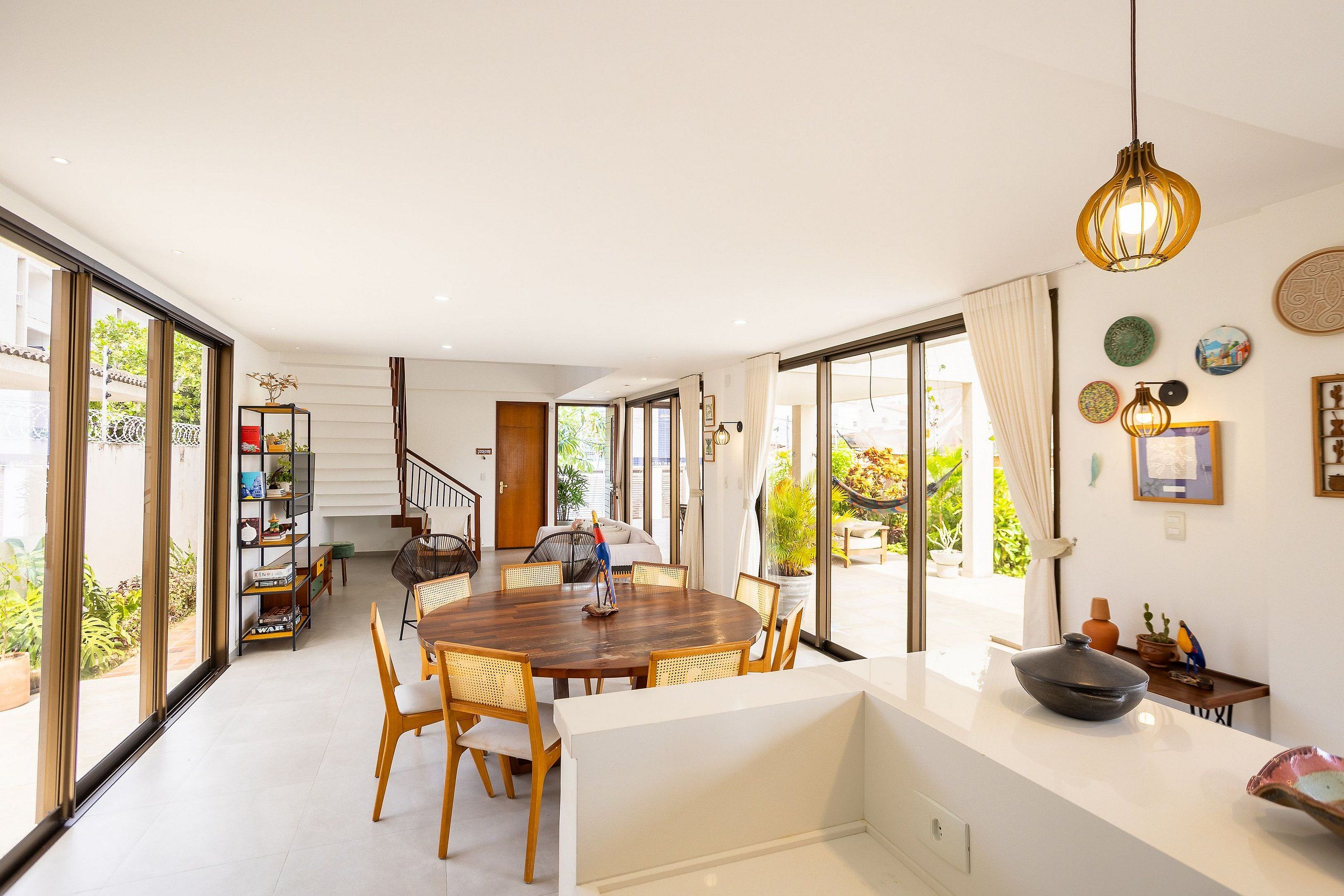 A spacious dining area with a round table, chairs, and a view of the outdoors through large windows.