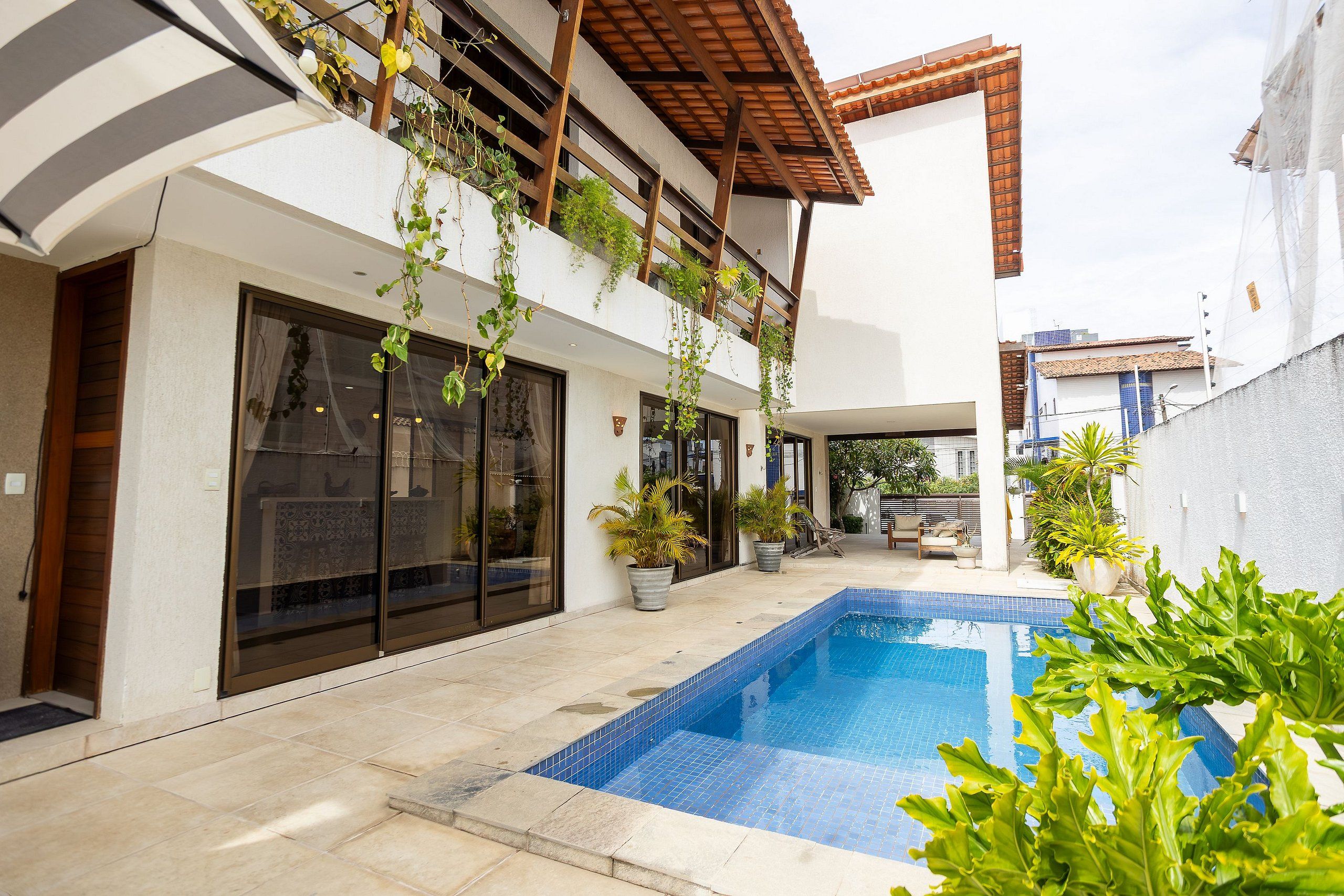A modern outdoor pool area with a tiled deck, a small pool, and potted plants.