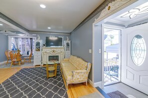 A living room with a fireplace, a sofa, a dining table with chairs, and a patterned rug.