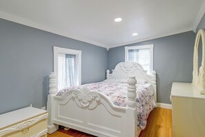 A bedroom with a white bed, a dresser, and a mirror.
