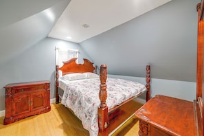 A bedroom with a wooden bed, a nightstand, and a dresser. - Updated Schenectady Home: 1 Mi to Downtown! (Schenectady)