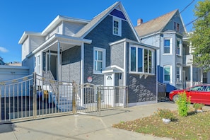 A two-story house with a stone facade, a gated driveway, and a red car parked in front.
