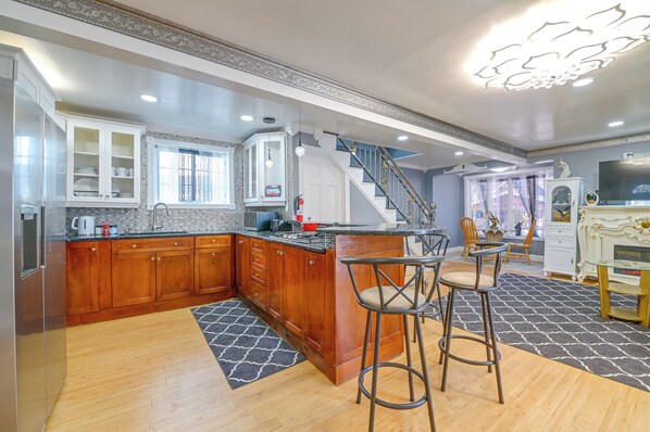 A modern kitchen with wooden cabinets, a marble countertop, and a built-in stove.