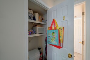 A hallway with a white door, a shelf with books and a microwave, and a colorful map on the wall. - Walk to Beach! Updated Brigantine Retreat (Brigantine)