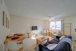 A living room with a TV, sofa, chairs, a dining table, and a window with a view of buildings. - Walk to Beach! Updated Brigantine Retreat (Brigantine)