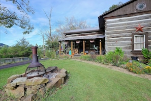 A rustic log cabin with a stone fire pit and a welcoming porch.