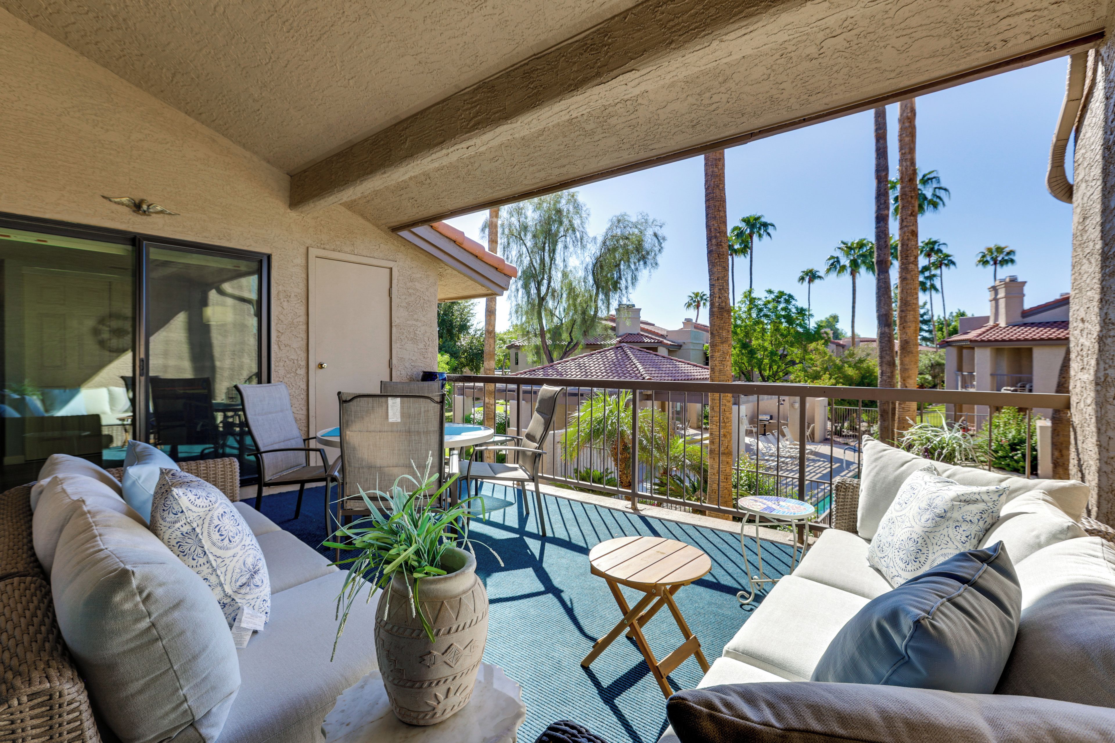 A balcony with a sofa, chairs, a small table, and a potted plant.