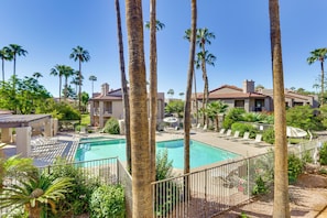 A swimming pool surrounded by palm trees and a building with a tiled roof. - Pool & Spa! Stylish 2nd-floor Scottsdale Retreat (Scottsdale)