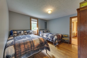 A bedroom with two beds, a window, and a door leading to another room. - Rural WV Escape w/ Hilltop Mountain Views (Mabie)