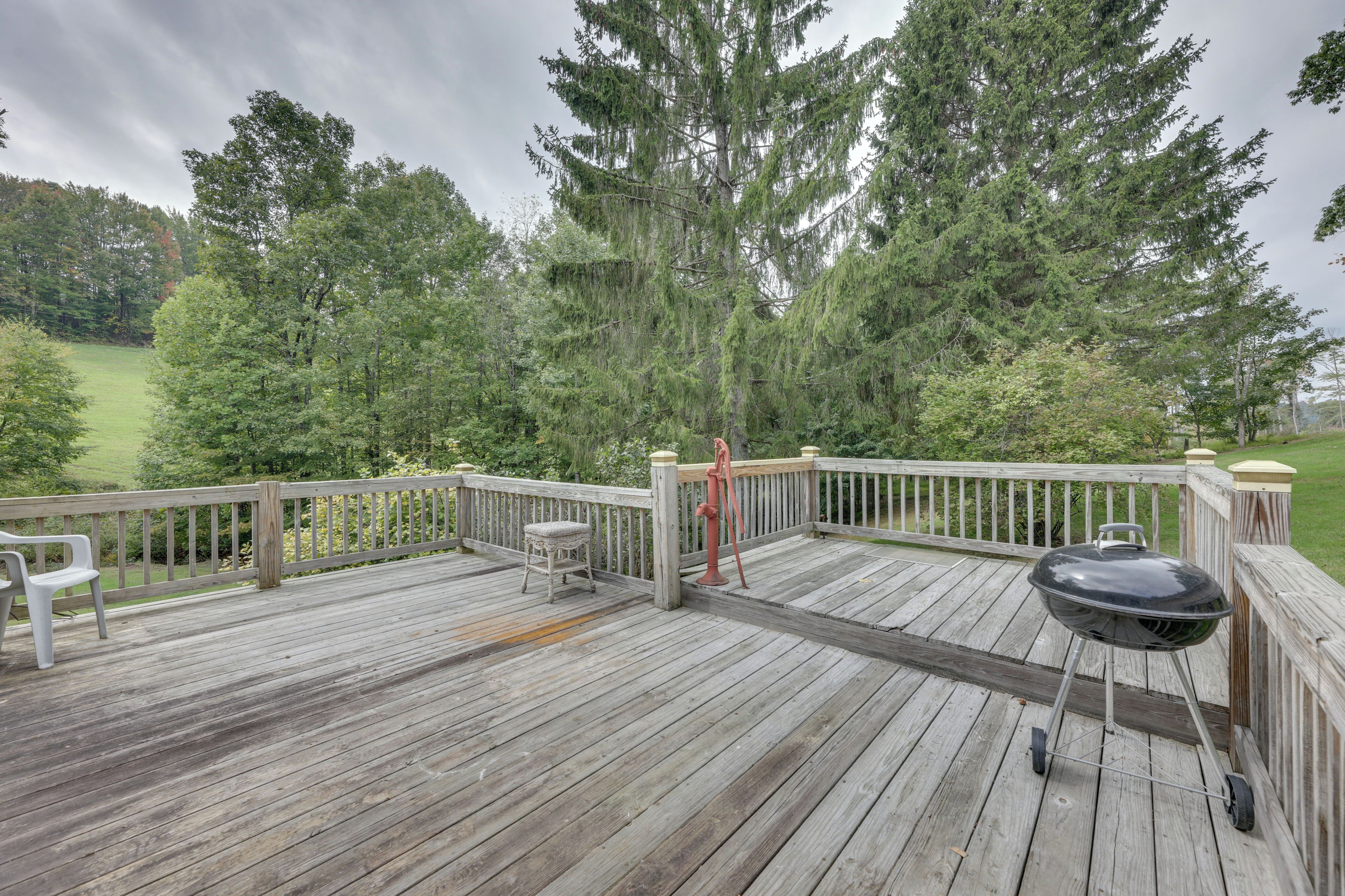 A wooden deck with a barbecue grill, a wooden chair, and a metal fire hydrant.