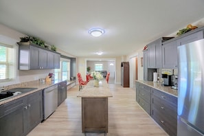 A modern kitchen with dark cabinetry, a central island, and a stainless steel refrigerator.