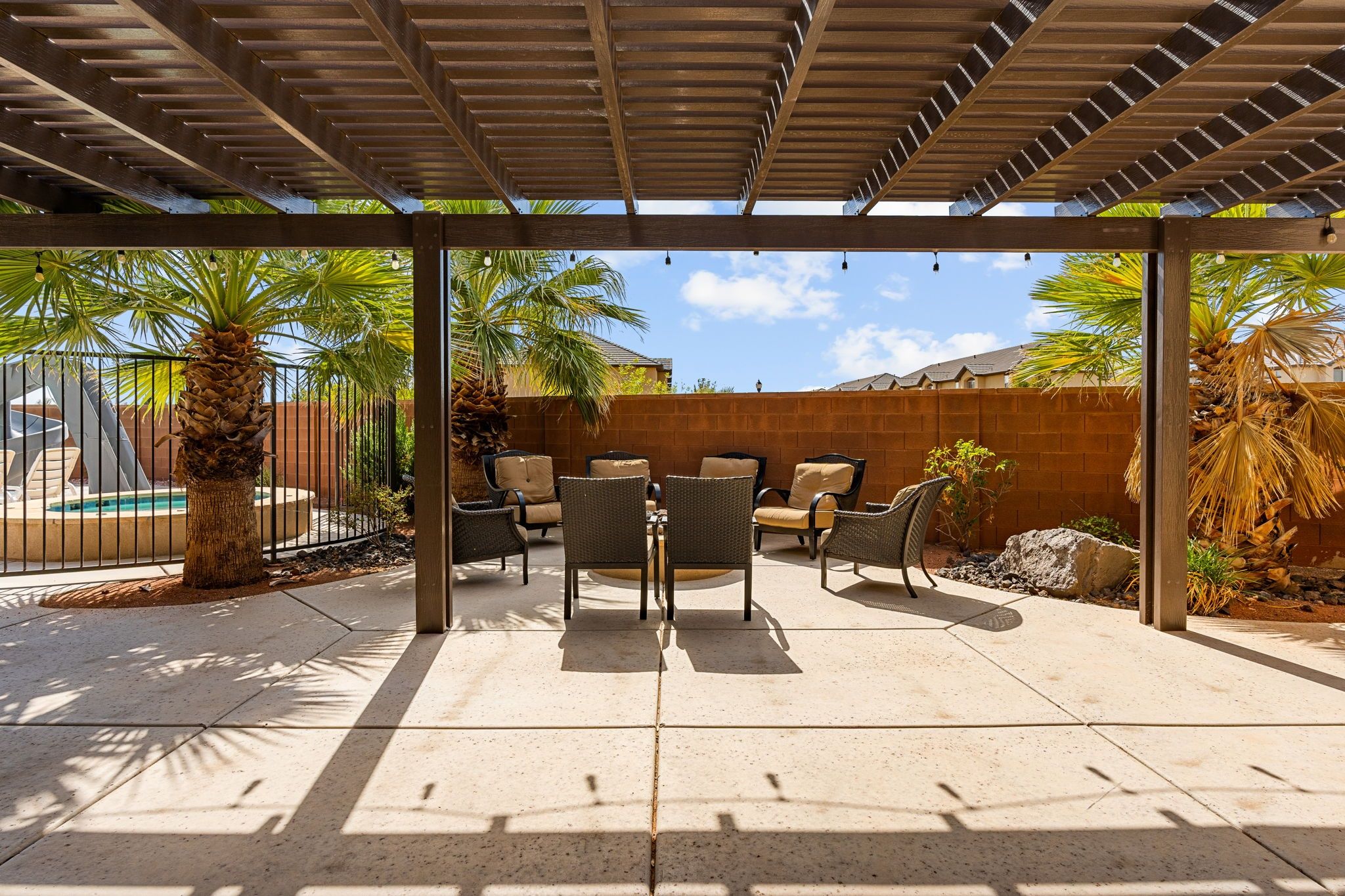An outdoor patio with a pergola, seating area, and pool.
